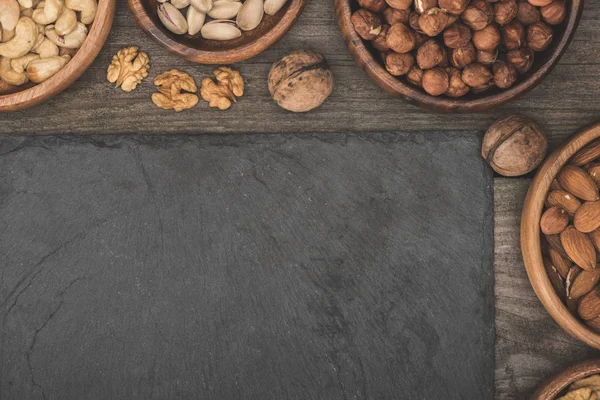 Nuts in bowls and slate board — Stock Photo