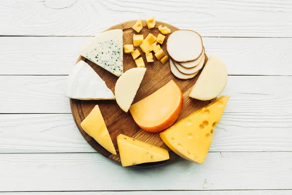 Tipos variados de queso en la tabla de cortar - foto de stock