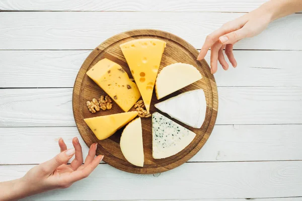 Female hands and arranged types of cheese — Stock Photo