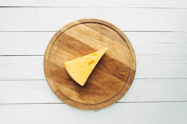 Pedaço de queijo na tábua de corte — Fotografia de Stock