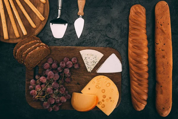 Verschiedene Käsesorten, Brot und Trauben — Stockfoto