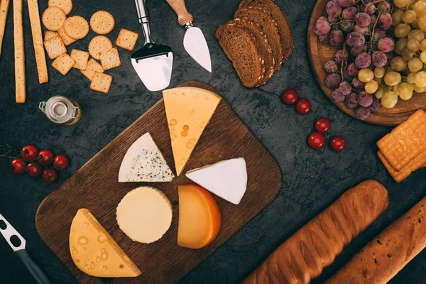 Varios tipos de queso, pan y uvas - foto de stock