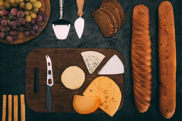 Varios tipos de queso, pan y uvas - foto de stock