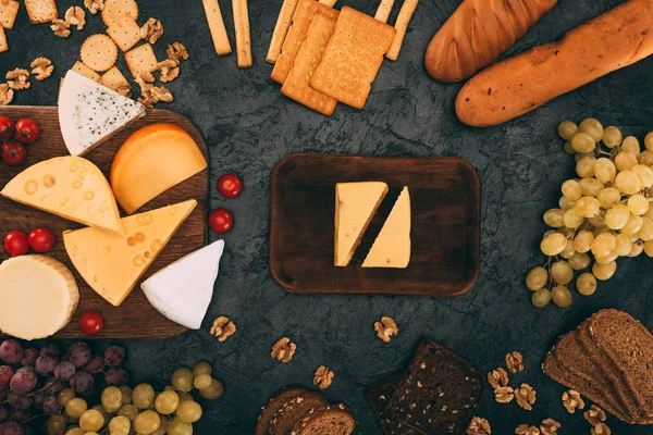 Varios tipos de queso, pan y uvas - foto de stock