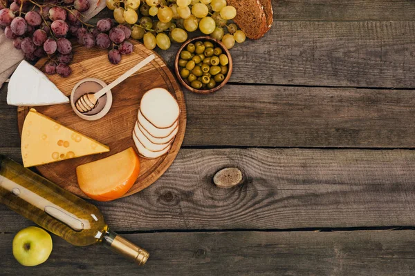 Botella de vino y queso en la tabla de cortar - foto de stock