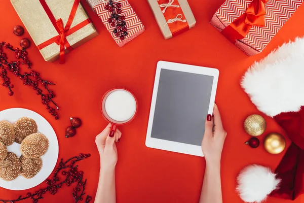 Hands with tablet and cup of milk — Stock Photo