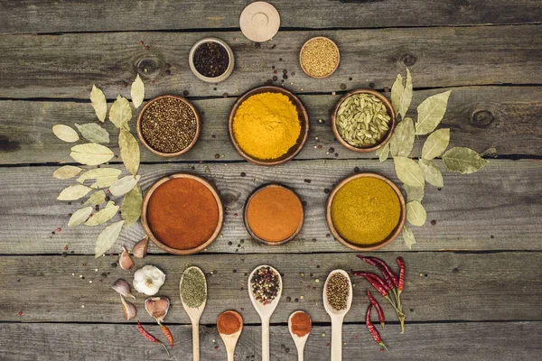 Bowls and wooden spoons with different spices — Stock Photo