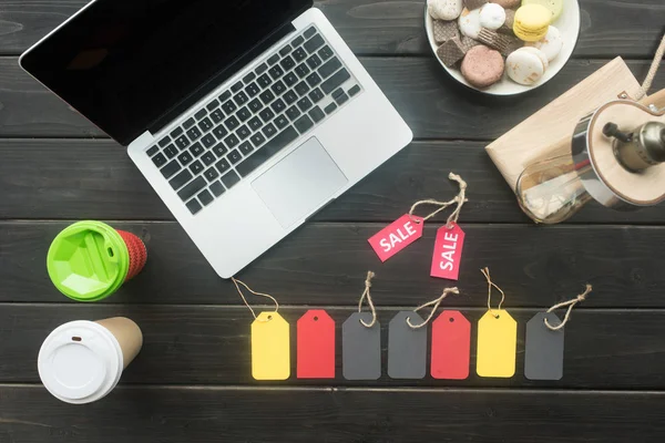 Laptop, macarons, coffee and sale tags — Stock Photo