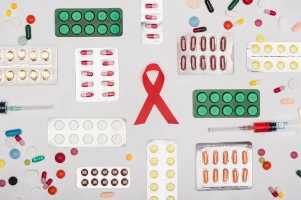 Aids ribbon with pills and syringes — Stock Photo