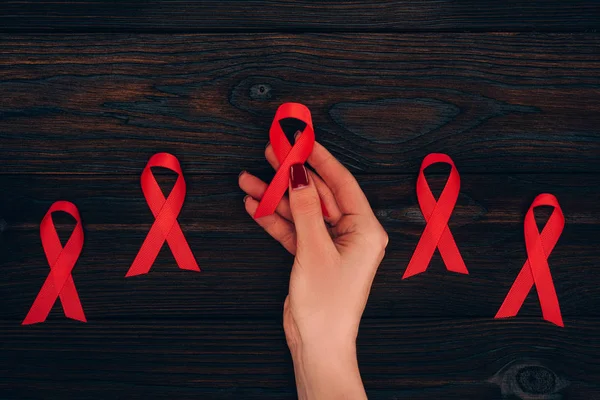 Hand with red aids ribbons — Stock Photo