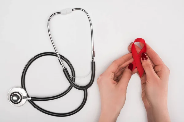 Hands with aids ribbon and stethoscope — Stock Photo