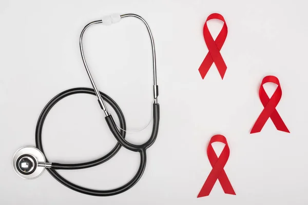 Stethoscope and red aids ribbons — Stock Photo