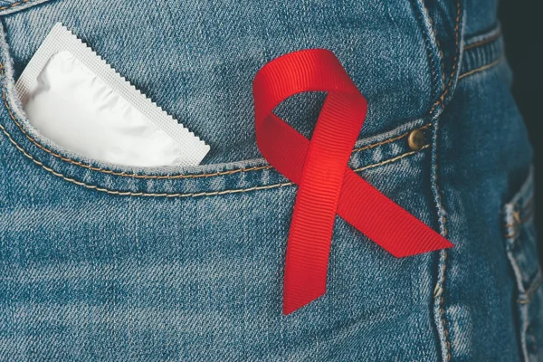 Condom and aids ribbon — Stock Photo