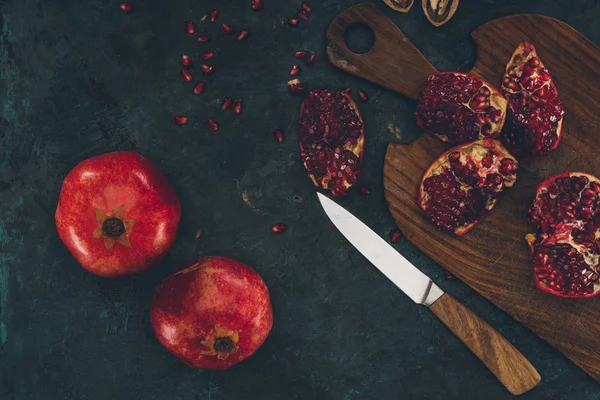 Knife and pomegranate on wooden board — Stock Photo