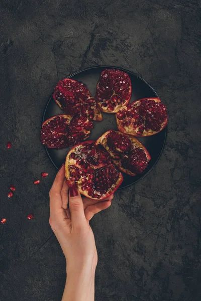 Woman taking piece of pomegranate — Stock Photo