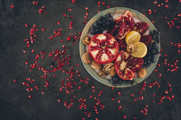 Piatto con melograni e uva con limoni — Foto stock