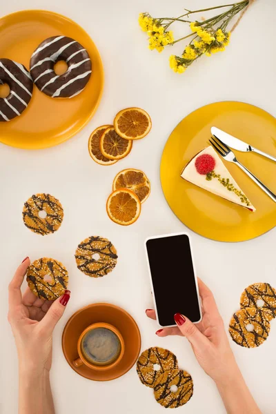 Hand with smartphone and cookies — Stock Photo