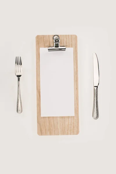 Blank paper on clipboard and cutlery — Stock Photo