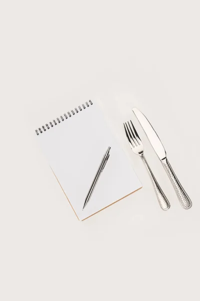 Notebook with pen and cutlery — Stock Photo