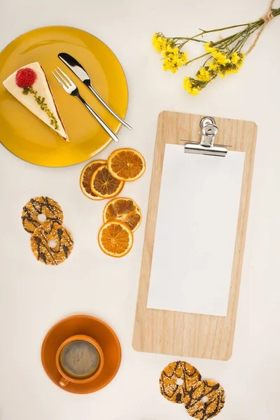 Sheet of paper on clipboard and dessert — Stock Photo