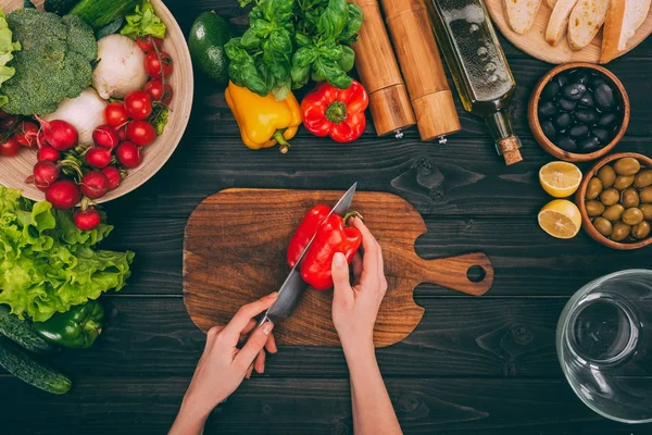 Hands slicing pepper by knife — Stock Photo