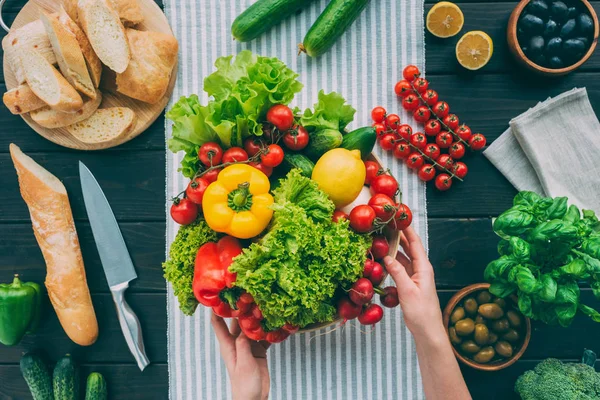 Mani che tengono la ciotola con verdure — Foto stock