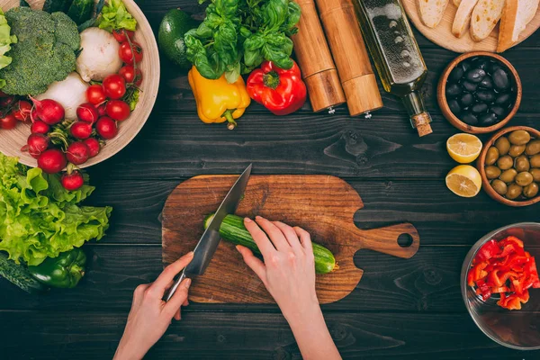 Hands slicing cucumber by knife — Stock Photo