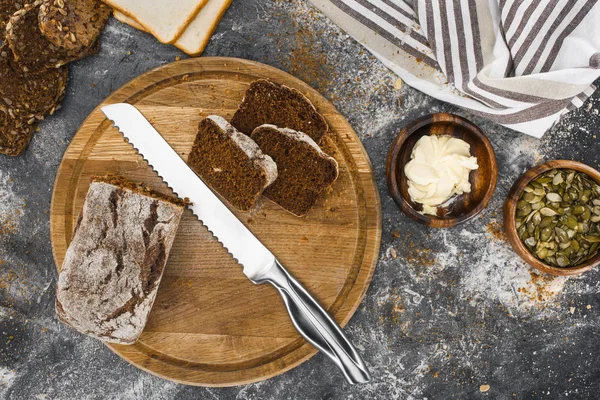 Pan y cuchillo en la tabla de cortar - foto de stock