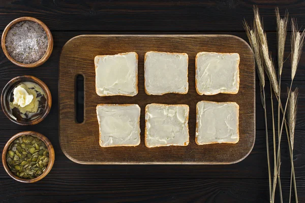 Toasts with butter on cutting board — Stock Photo