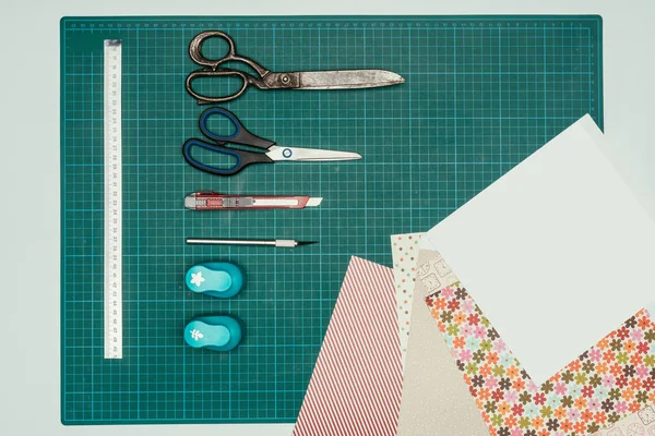 Top view of sheets of paper and scissors with stationery knife for making scrapbooking postcard — Stock Photo