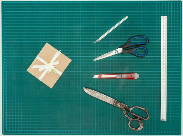 Top view of handmade present with scissors and knifes on turquoise surface — Stock Photo