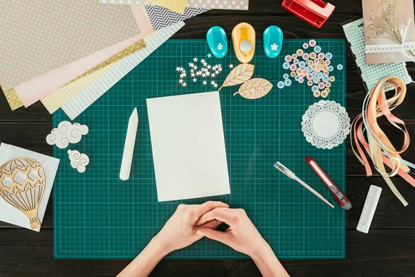 Cropped image of designer sitting at table with empty white sheet of paper — Stock Photo