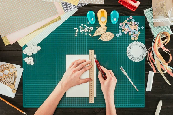 Cropped image of woman cutting paper for scrapbooking postcard — Stock Photo