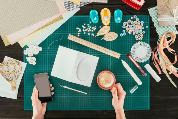 Cropped image of artist holding smartphone and cup of coffee in hands — Stock Photo