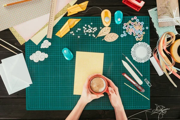 Cropped image of woman holding cup of coffee above working table — Stock Photo