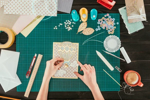 Cropped image of woman adding decorative clouds on scrapbooking handmade postcard — Stock Photo