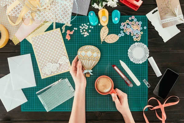 Imagem recortada de mulher segurando decorativo balão de madeira e xícara de café nas mãos — Fotografia de Stock