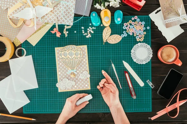 Cropped image of woman decorating scrapbooking postcard with star — Stock Photo