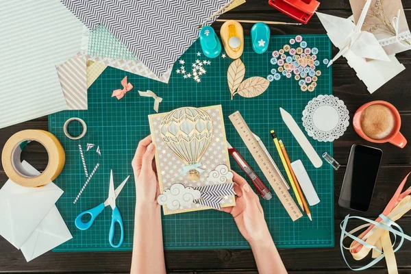 Cropped image of woman holding scrapbooking postcard with wooden balloon — Stock Photo