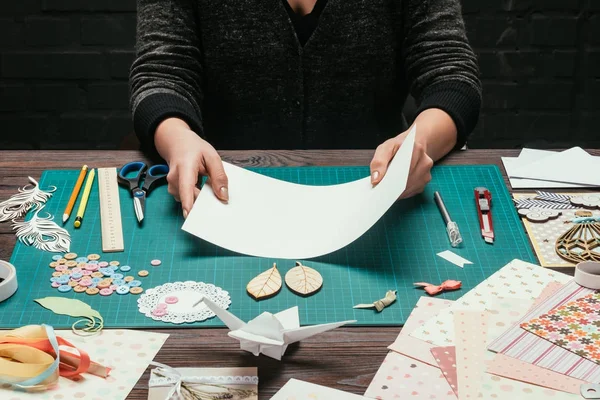 Cropped image of woman holding empty sheet of paper for scrapbooking handmade postcard — Stock Photo