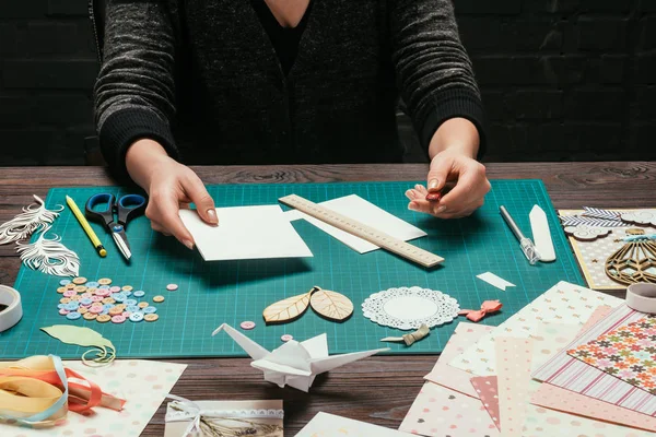 Imagen recortada de diseñador que sostiene la hoja de papel para la tarjeta postal hecha a mano scrapbooking - foto de stock