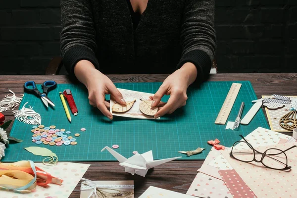 Abgeschnittenes Bild eines Designers, der Holzblätter zum Postkartencover von Scrapbooking hinzufügt — Stockfoto