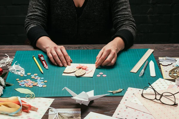 Cropped image of designer sitting with scrapbooking handmade postcard — Stock Photo