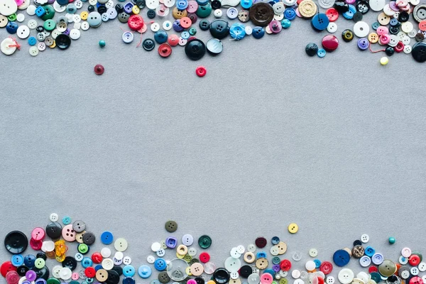 Vue de dessus du cadre de boutons colorés sur fond de tissu gris — Photo de stock
