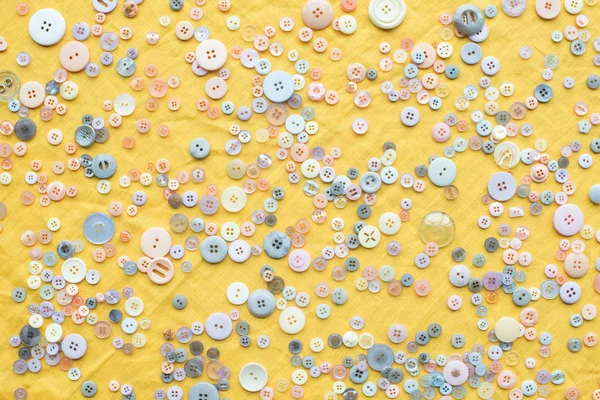 Вид зверху розсіяних барвистих кнопок на жовтому тканинному фоні — стокове фото