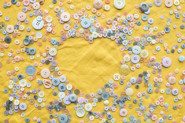 Vista superior de botones coloridos marco en forma de corazón sobre fondo de tela amarilla con espacio de copia - foto de stock