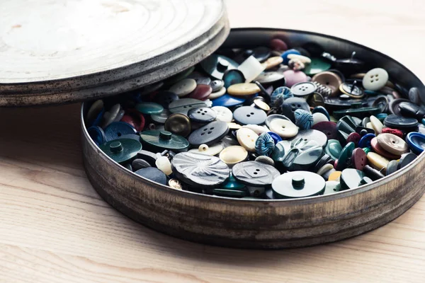 Lot of buttons in circle box over wooden background — Stock Photo