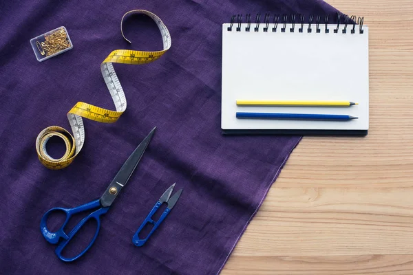 Vista superior da tabela com ferramentas de costura sobre tecido roxo — Fotografia de Stock