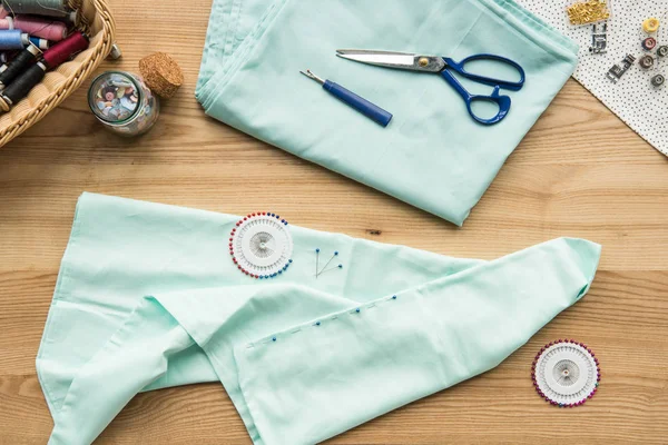 Top view of seamstress workplace on table with fabric, scissors, needles, measuring tape and buttons — Stock Photo