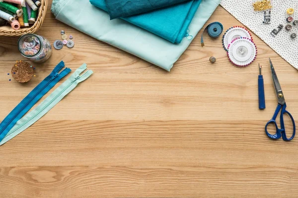 Vista superior do local de trabalho de costureira na mesa com tecido, tesoura e armários com zíper — Fotografia de Stock
